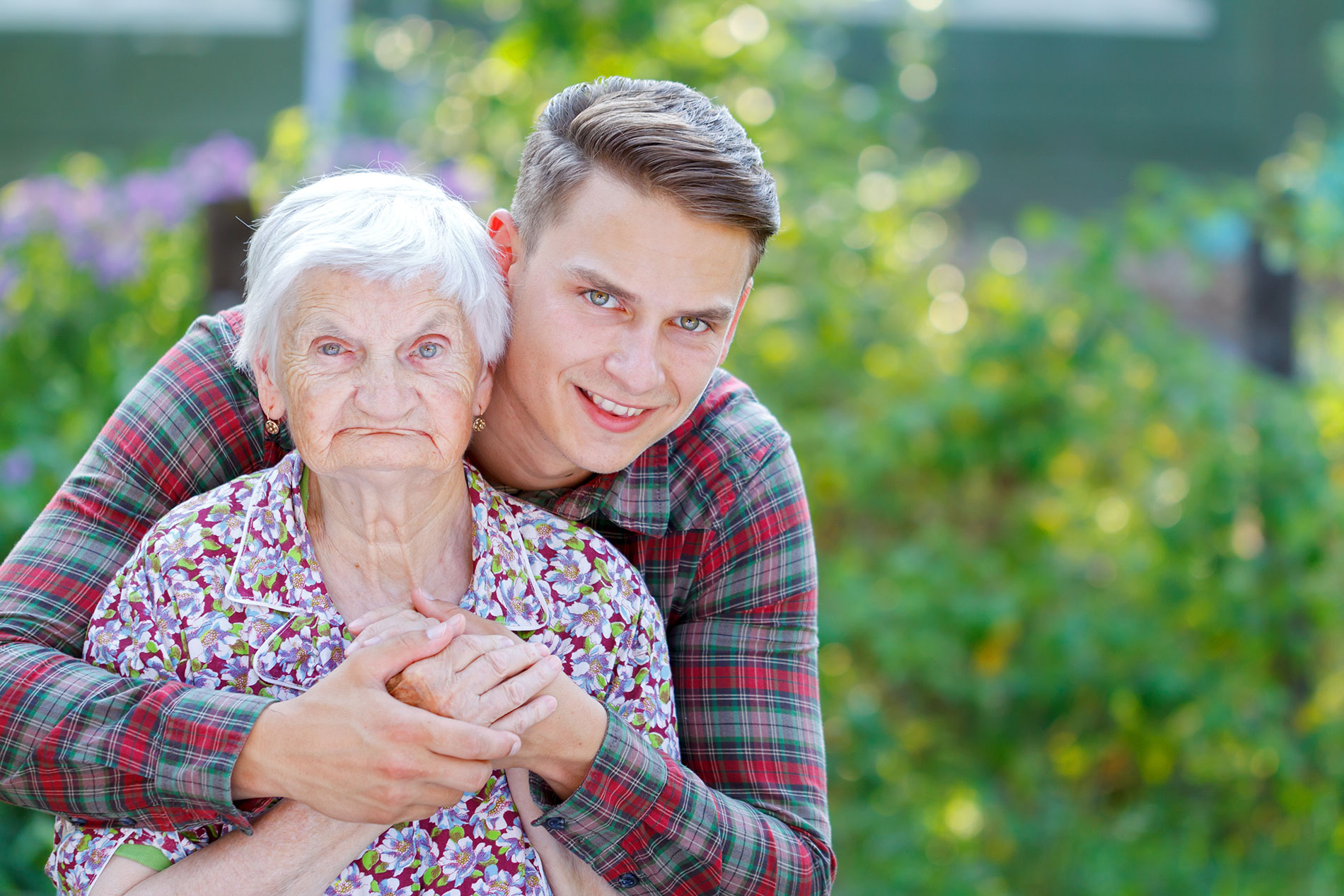 Пожилая женщина любит молодую. Бабушка обнимает. Объятия пожилых. Бабушка и внук. Пожилые родители и взрослые дети.